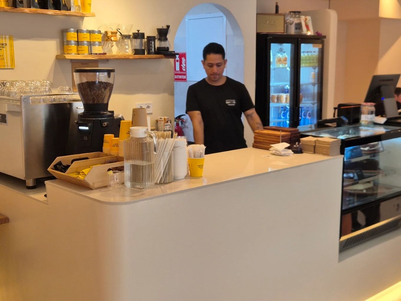 La barra: molinillo, estanterías con café y el arco hacia la cocina