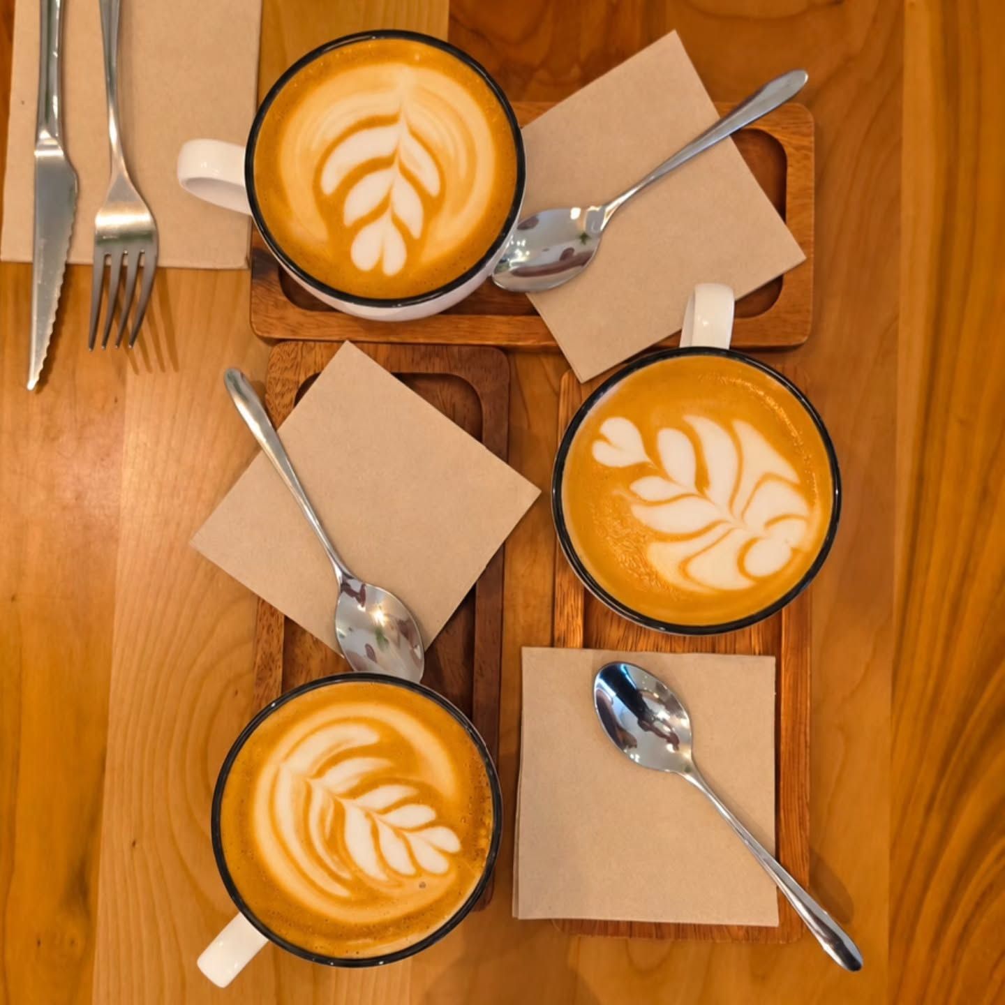 Tres cafés con leche con arte latte, vistos desde arriba